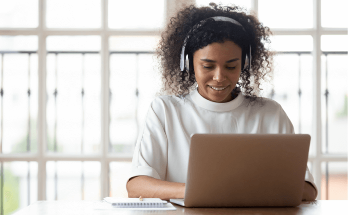 Student working on online course. A woman wearing headphones working on some work for her online Master of Computer Science class on the computer.