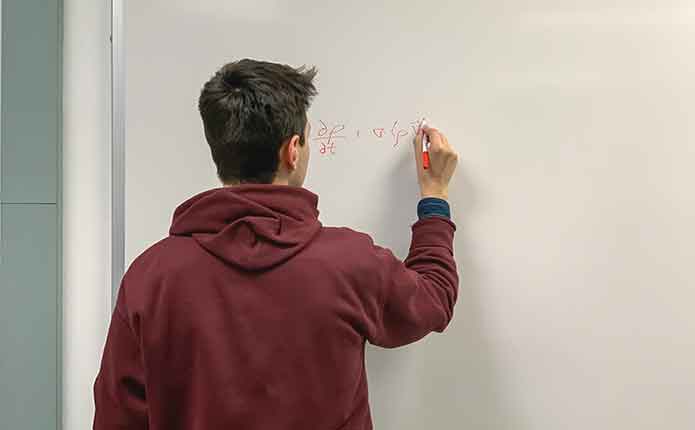 A student on the whiteboard. A male student on the whiteboard solve a problem for online Master of Computer Science class.