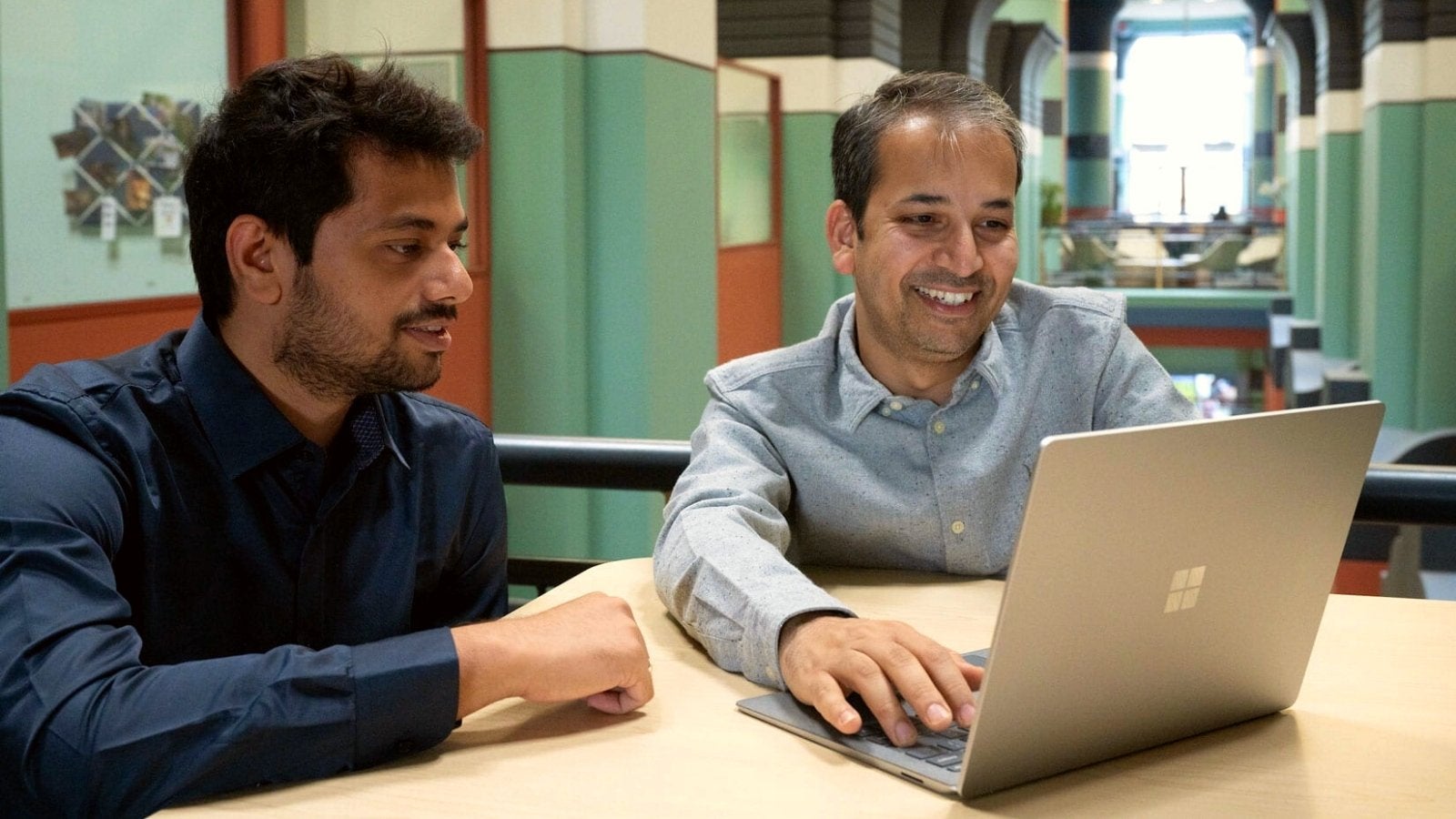 Aditya Desai and Anshumali Shrivastava sit in front of a laptop and talk inside Duncan Hall at Rice University