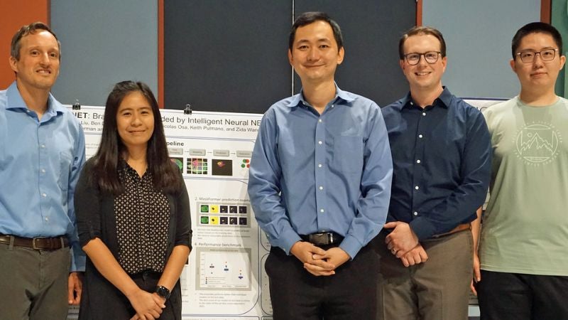 Chevron Digital Scholars stand next to research poster presentation