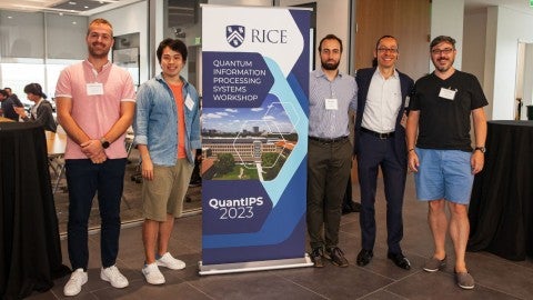 Rice quantum workshop members stand next to the event banner